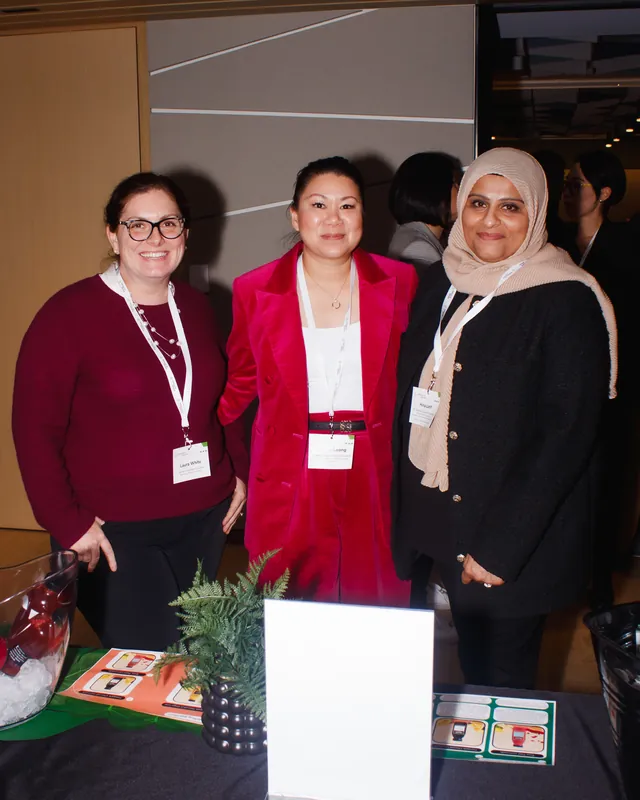 Three attendees smiling beside a display at a business event